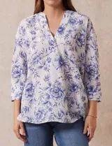 Blusa estampada con flores azules sobre fondo blanco, marca Floral & Ivy. Tiene cuello a la base con escote en V y aplique de botones. Las mangas son tres cuartos con puño y botón. Presenta tajos en las costuras laterales.