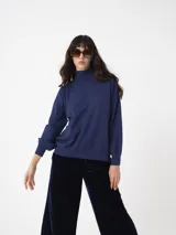 Sweater de cuello alto con mangas amplias y puños ajustados, confeccionado en tejido de punto con acabado liso.