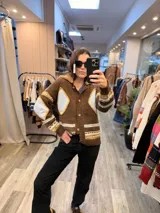 Campera tejida de punto en color marrón con diseño de rombos en tonos celestes y amarillos. Presenta cuello con detalle de corderito, cierre frontal con botones y puños acanalados.