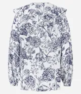 Blusa blanca estampada con flores azules, de mangas largas abullonadas con puños ajustados y volado en el cuello.