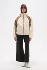 Campera de abrigo de tejido polar (tipo sherpa) color gris oscuro, con capucha y cierre frontal. Presenta paneles de color negro en los hombros y mangas, ribeteados con un vivo de color claro.