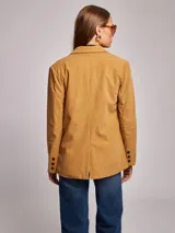 Blazer color ocre de pana con cuello y solapa, manga larga, bolsillos delanteros con solapa y cierre frontal con dos botones.