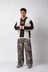 Sweater de punto con diseño a rayas verticales en color beige y blanco, de corte holgado y cuello polo abierto. Presenta un logo bordado en el centro del pecho.