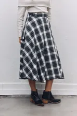Falda midi de corte acampanado con estampado de cuadros escoceses en tonos blanco y negro. Presenta un diseño de cintura alta con detalle de solapa y cierre lateral.