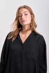 Camisa negra de lyocell con cuello clásico, cierre frontal con botones, manga larga y bolsillo en el pecho.