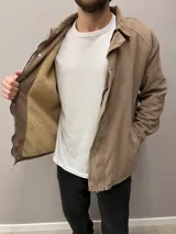 Campera de pana color tostado con forro de corderito, cierre frontal con cremallera y botones a presión, cuello camisero y bolsillos laterales.