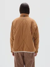 Campera marrón claro con diseño acolchado de rombos, cuello alto, cierre frontal con cremallera, bolsillos laterales y mangas largas con rayas blancas.