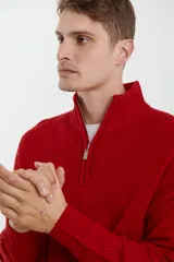 Sweater verde de punto inglés con cuello alto y cierre metálico frontal. Tiene mangas largas y terminaciones en punto canalé.