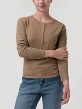 Remera de manga larga color beige, con cuello redondo y cierre frontal parcial con botones. Presenta un diseño de tejido trenzado con textura de rombos en las mangas y cuerpo liso.