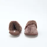 Pantuflas tipo mule color marrón, confeccionadas en material aterciopelado con borde de pelo sintético en la parte superior y suela plana.