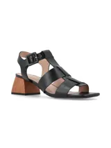 Sandalia de cuero negro con diseño de tiras anchas entrelazadas, cierre con hebilla lateral y taco cuadrado de madera.