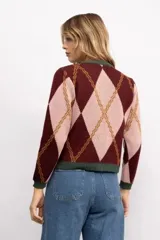 Cardigan de punto con patrón argyle en tonos gris y naranja, con cuello redondo, cierre frontal de botones dorados y bordes en color bordó.
