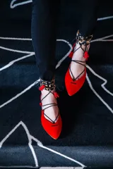 Bailarinas rojas de punta fina con talonera de animal print, pulsera tobillera de pelo de pony con estampado animal print y borlas rojas.