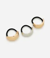 Kit de tres gomitas elásticas negras para el cabello, cada una con un aplique metálico decorativo de diseño curvo en tonos dorado y plateado.