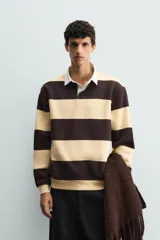 Sudadera tipo polo de corte regular, color gris claro, con cuello solapa en color blanco y cierre frontal de botonadura oculta. Presenta mangas largas con puños y ruedo en rib.