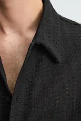 Camisa regular fit de manga corta confeccionada en tejido jacquard con estructura abierta y diseño geométrico. Presenta cuello solapa y cierre frontal con botones al tono.
