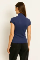 Top de manga corta color beige claro, de tejido acanalado y corte ajustado al cuerpo, con cuello tipo polera (mock neck).