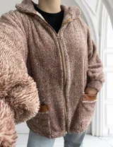 Campera de abrigo color marrón claro, estilo teddy, con cierre frontal y bolsillos con ribete de cuero sintético.