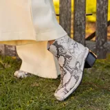 Botín de cuero con estampado de piel de serpiente en tonos blanco y negro, con puntera cuadrada y tacón bloque bajo.