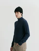 Cardigan de punto color azul marino, con cuello alto y cierre frontal parcial. Presenta diseño de punto inglés en cuerpo y mangas, con terminaciones en punto canalé en cuello y puños.