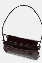 Bolso de hombro con solapa y acabado efecto acharolado. Cuenta con asa ajustable y cierre mediante imán.