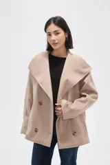 Tapado corto de paño en color beige, con cuello solapa amplio y cierre frontal cruzado con doble botonadura. Presenta mangas largas y bolsillos laterales integrados.