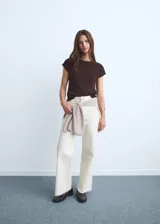Jeans blancos de tiro alto, corte culotte y bajo deshilachado, con cierre de cremallera y botón, trabillas y bolsillos traseros.