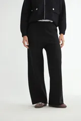 Pantalón de tejido de punto color negro, de corte recto y holgado, con cintura elástica y bolsillos laterales.