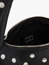 Bolso de hombro negro de efecto cuero, con forma curva y asa superior. Está completamente decorado con tachuelas metálicas redondas plateadas. Posee cierre superior con cremallera.