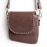 Mini cartera bandolera de cuero, de formato compacto y diseño atemporal con solapa frontal y costuras artesanales decorativas en el borde. Cuenta con el logotipo de la marca grabado en la parte delantera y correa larga regulable.