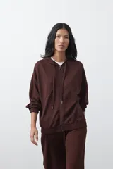 Campera con capucha y cierre frontal, de silueta relajada, hombros caídos y bolsillos laterales. Presenta terminaciones elastizadas en puños y ruedo, con líneas de recorte frontales y cierre metálico con tirador circular.