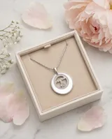 Dije circular de plata 925 con incrustación de nácar, borde decorado con circonias y diseño central calado con la palabra mama y una figura de niña.