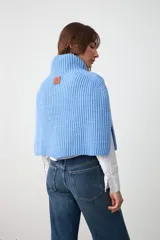 Capita tejida en punto acanalado color celeste, con cuello alto y aberturas laterales.