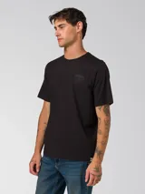 Remera de algodón de corte clásico y cuello redondo, color negro. Presenta un diseño minimalista con un pequeño gráfico bordado en el pecho y un parche de la marca en la manga izquierda.