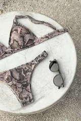 Conjunto de bikini con estampado de piel de serpiente en tonos rosados y negros. El top es de estilo triángulo fijo con breteles regulables y cierre de gancho en la espalda. La bombacha es de corte vedetina con laterales fruncidos.