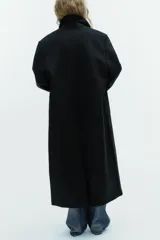 Abrigo largo de corte recto confeccionado en mezcla de lana. Presenta cuello con solapas de muesca, cierre frontal cruzado con doble botonadura y bolsillos laterales de vivo.