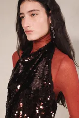 Vestido largo de lentejuelas con cuello halter, espalda descubierta y lazos para atar al cuello. Cuenta con un cinturón de lazo en contraste y diseño bicolor que combina tonos tostados y negros.