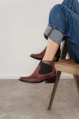 Botín negro de cuero con elásticos laterales, taco bajo y tirador trasero.