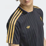 Remera de fútbol Adidas del Manchester United, con diseño a rayas verticales negras y violetas, detalles dorados en cuello, mangas y logo.