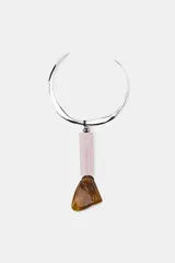 Collar choker metálico plateado con un colgante compuesto por una pieza cilíndrica de resina rosa y una pieza irregular de resina marrón ámbar.