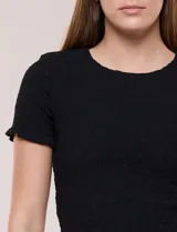 Blusa de calce al cuerpo con textura elastizada fruncida y diseño de rombos, cuello redondo de terminación ondulada, mangas cortas y ruedo con acabado ondulado.