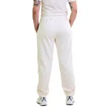 Pantalón deportivo de mujer color blanco hueso, con cintura elástica y cordón ajustable. Presenta un pequeño logo negro en el muslo izquierdo y puños ajustados en los tobillos.