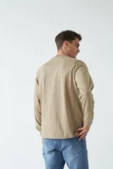 Remera de manga larga blanca con cuello redondo y estampado frontal con imagen de un pianista y texto en color celeste.