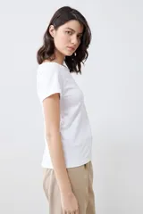 Remera de manga corta con escote bote, confeccionada en tejido liso de color blanco, con un corte ajustado y versátil.