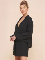 Blusa Allie Rose de color negro, corte holgado con escote en V cruzado y cuello camisero. Presenta mangas largas amplias con puños sutilmente fruncidos y diseño de silueta fluida.