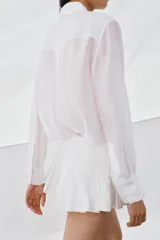 Camisa de corte fluido con cuello solapa y manga larga con puños. Presenta detalles de bordados a tono en el frente y cierre frontal con botones ocultos bajo solapa.