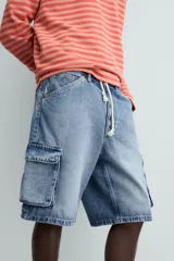 Bermuda de denim de algodón, color celeste lavado, de corte relajado (relaxed fit). Presenta cinco bolsillos, incluyendo bolsillos cargo plastrón con solapa en las perneras.