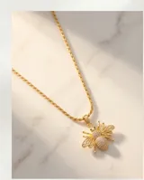 Cadena de acero con baño de oro y dije de bronce en forma de abeja, decorado con circonias brillantes.