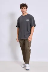 Remera de corte oversize color gris oscuro con efecto lavado, cuello redondo y estampa pequeña en el pecho.