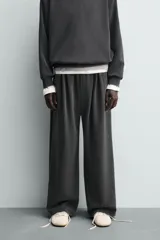 Pantalón jogger de corte wide fit confeccionado en tejido fluido con viscosa. Presenta un efecto lavado, cintura elástica ajustable con cordón, pliegues frontales, bolsillos laterales y un bolsillo trasero de plastrón.